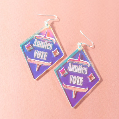 Diamond shaped iridescent earrings with formline cut out and 'Aunties Vote' engraved in the middle from copper canoe woman