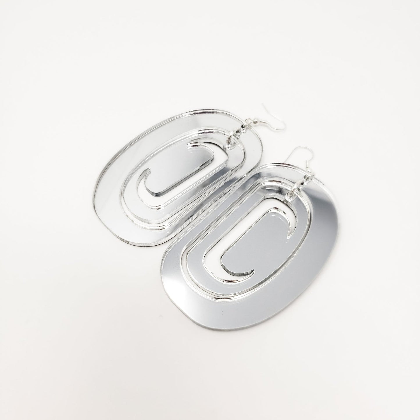 Large ovoid earrings from Copper Canoe Woman with trigon cutout in silver mirror acrylic.