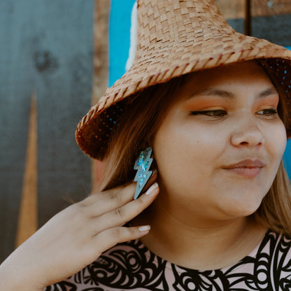 model wearing acrylic black lightning bolt earring with abalone inlay from copper canoe woman. 