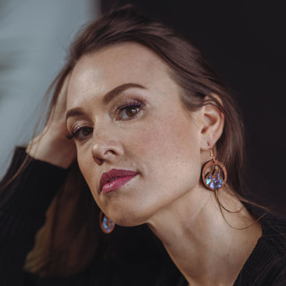 woman wearing cedar earring with mountain cut out and abalone inlay from copper canoe woman