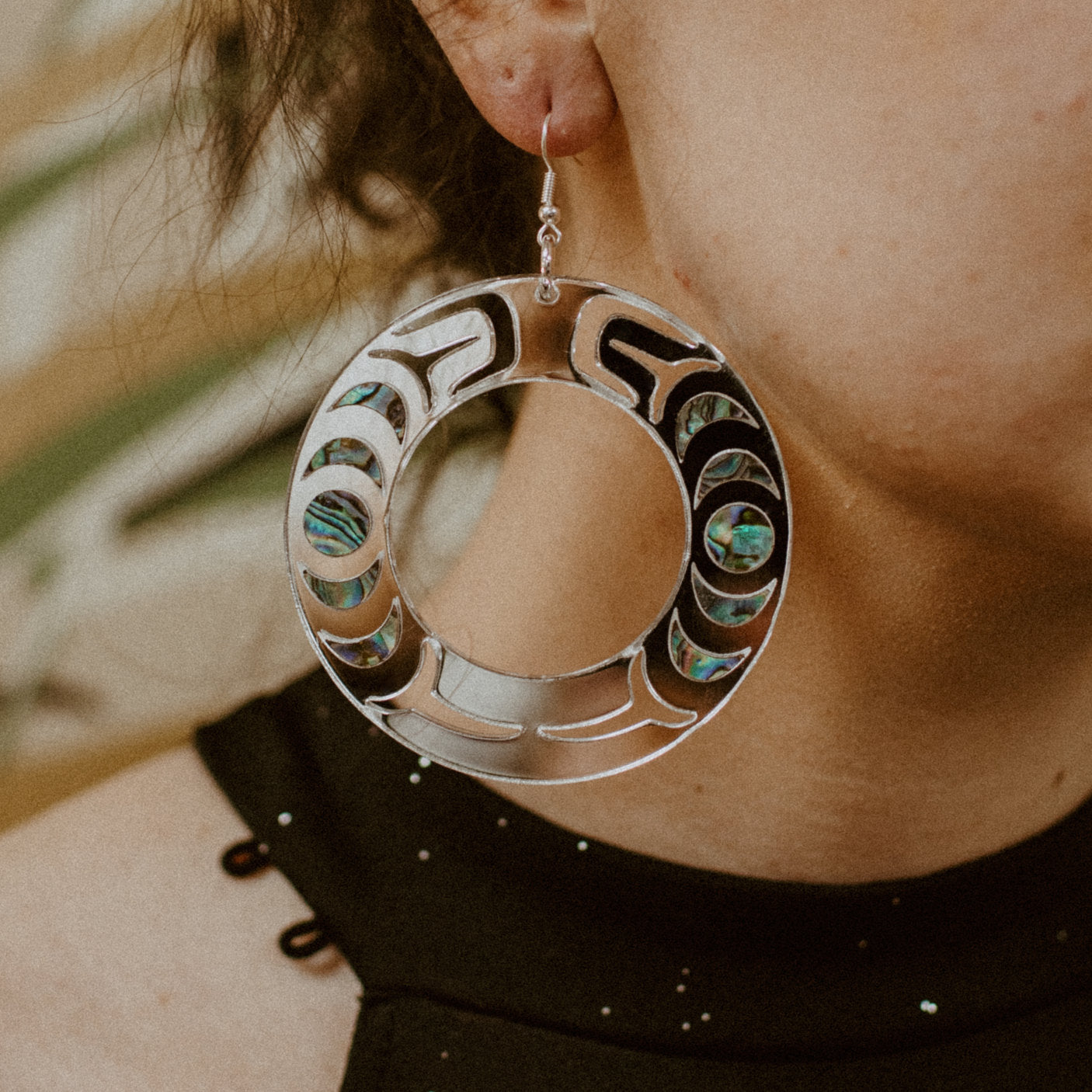 Closeup of model wearing the silver mirror acrylic "Nala Hoop" earrings from Copper Canoe Woman.