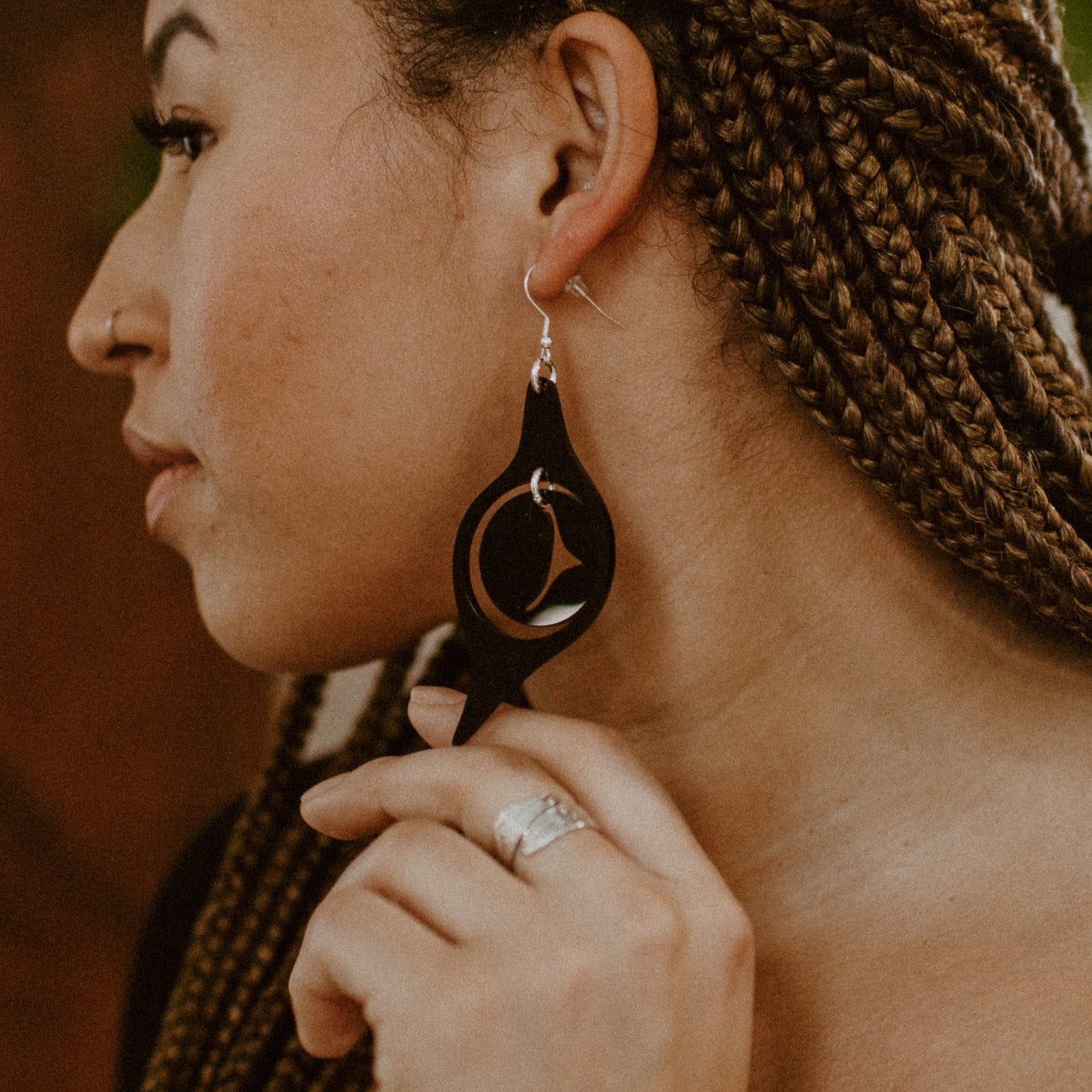 A model in profile wearing the octopus eye earring from Copper Canoe Woman in black acrylic.