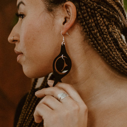 A model in profile wearing the octopus eye earring from Copper Canoe Woman in black acrylic.