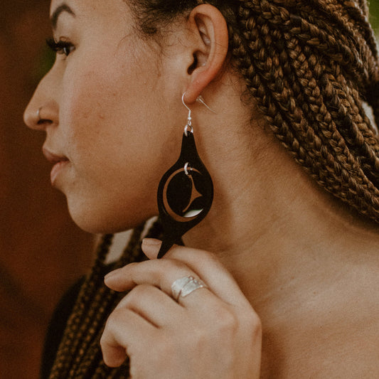 A model in profile wearing the octopus eye earring from Copper Canoe Woman in black acrylic.