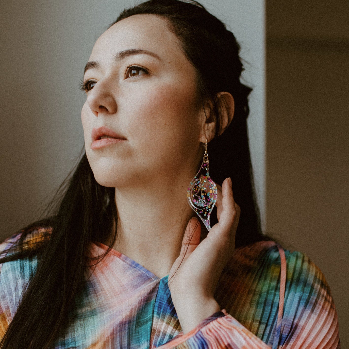 A pair of confetti glitter acrylic "Octopus Eye" earrings from Copper Canoe Woman worn by a model.