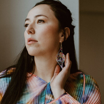 A pair of confetti glitter acrylic "Octopus Eye" earrings from Copper Canoe Woman worn by a model.