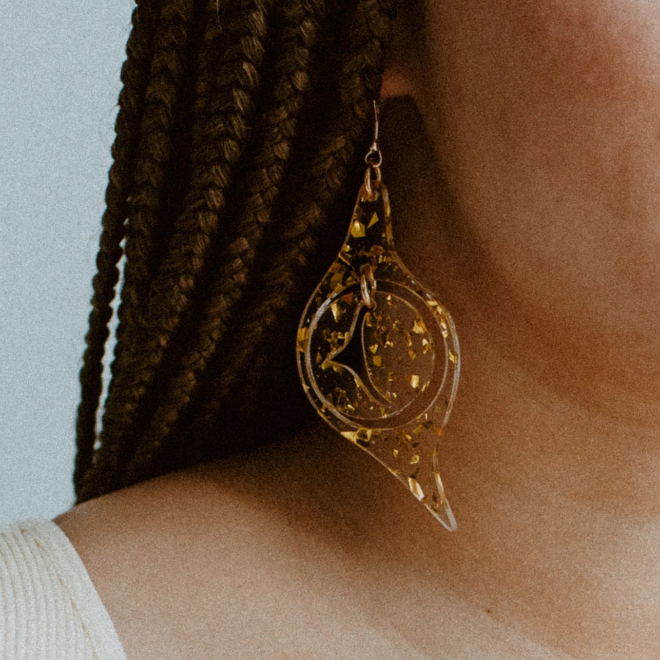 A model wearing "Octopus Eye" earrings in gold flake acrylic from Copper Canoe Woman.