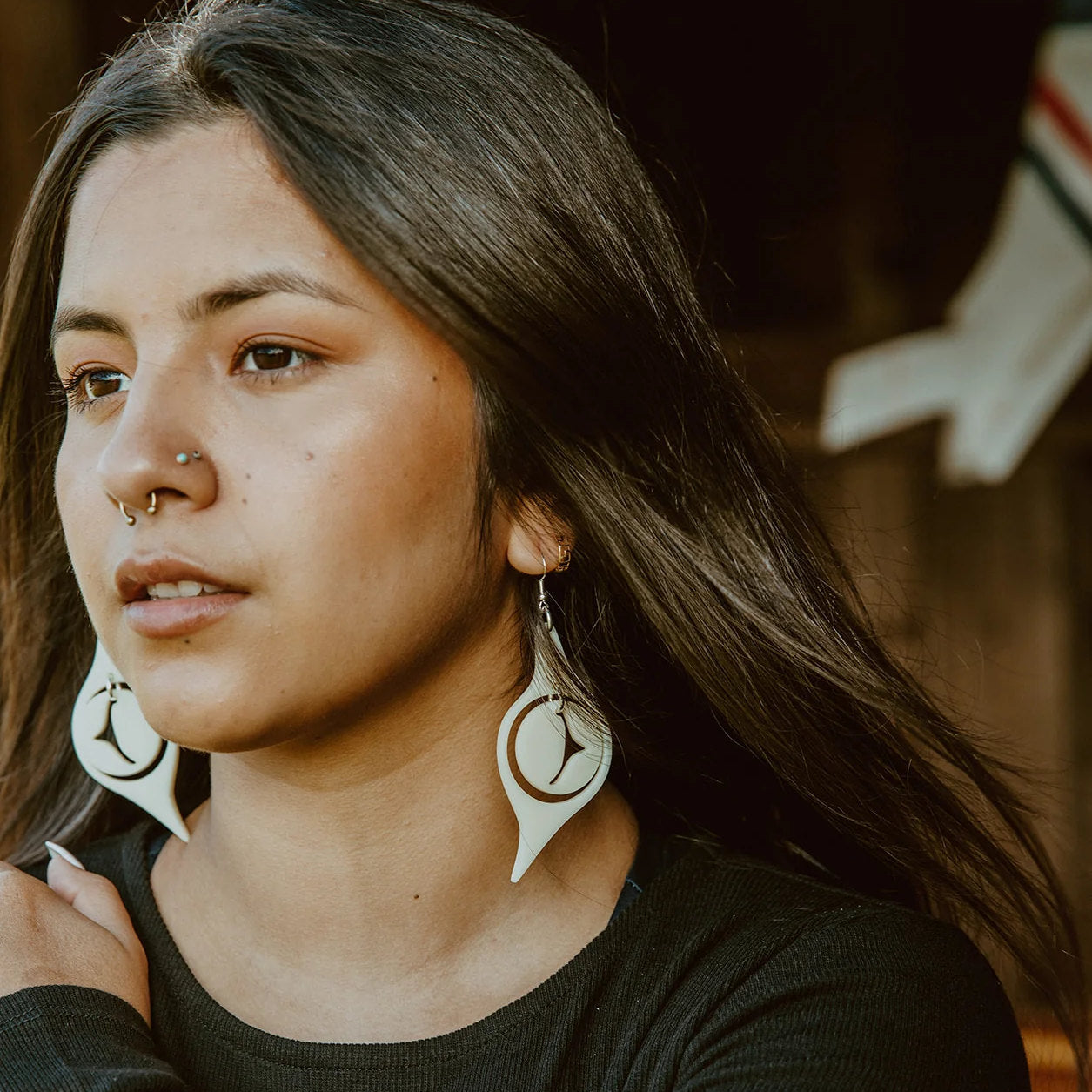 A model wearing ivory acrylic "Octopus Eye" earrings from Copper Canoe Woman.
