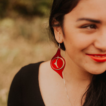 A model in a field wearing red acrylic "Octopus Eye" earrings from Copper Canoe Woman.