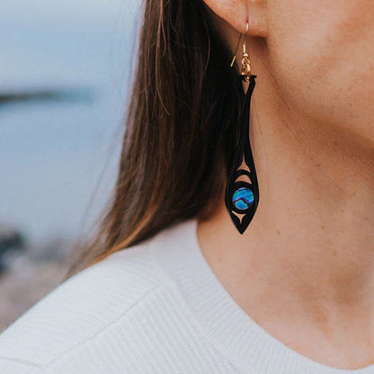 A closeup of a model wearing the black acrylic "Paddle Song" earring from Copper Canoe Woman.