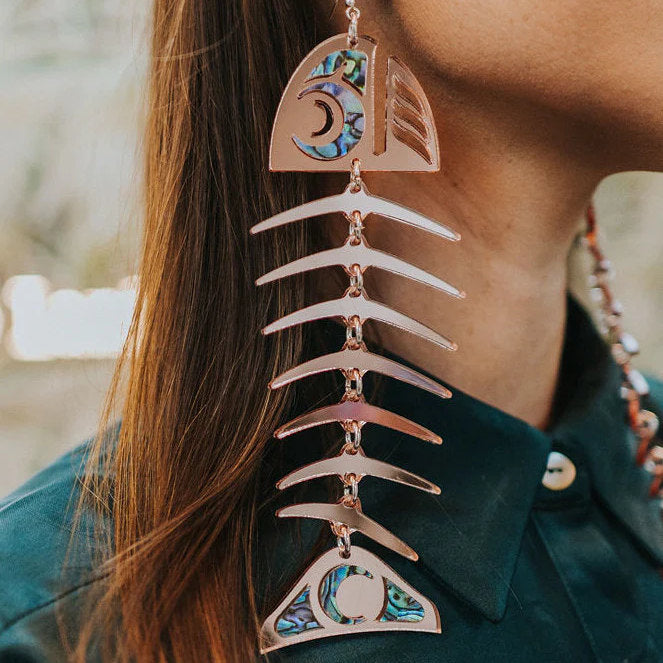 Copper Canoe Woman large salmon ghost earrings in rosegold mirror acrylic worn by a model.
