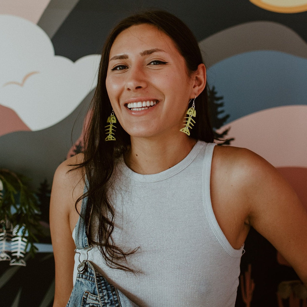 A smiling model wears neon pear acrylic small salmon ghost earrings from Copper Canoe Woman.