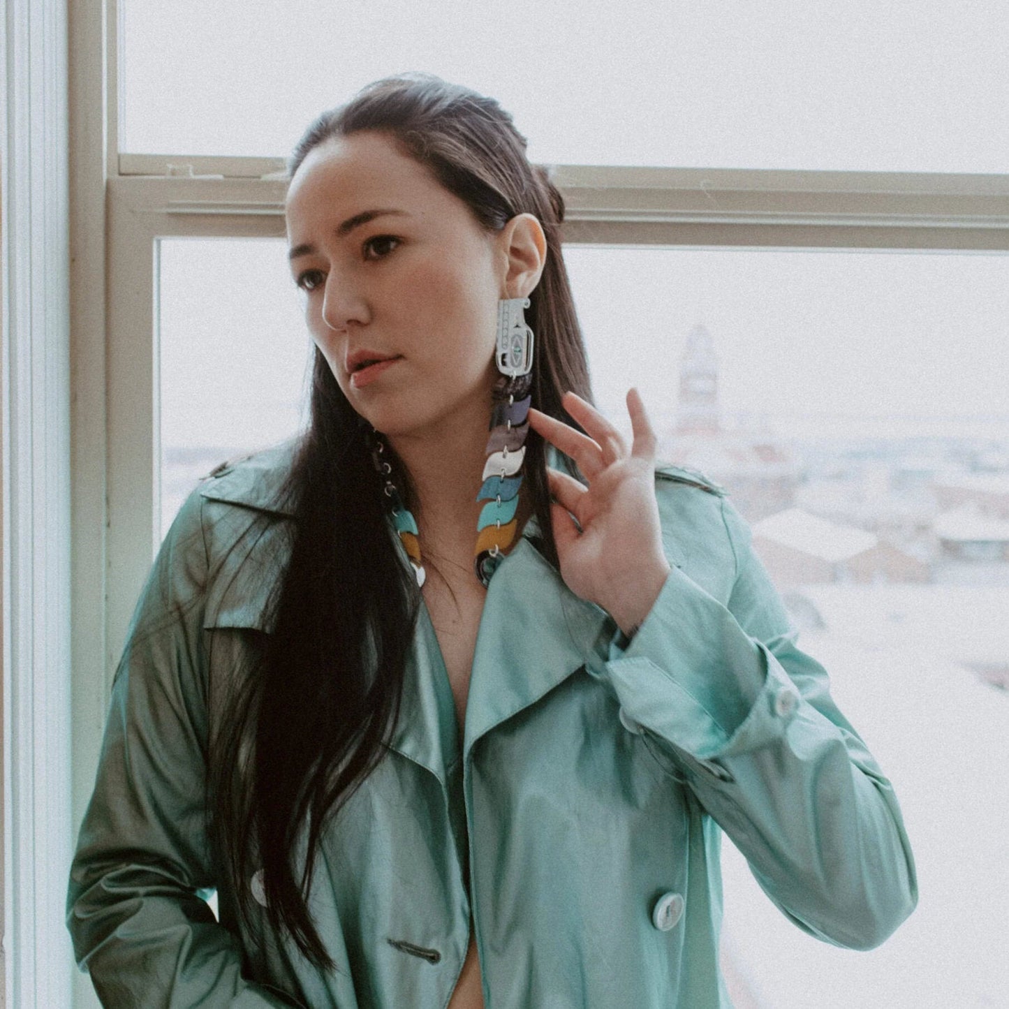 A model wears the serpent earrings from Copper Canoe Woman in blue and silver mirror acrylic.