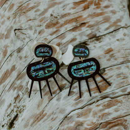 Urchin earrings in black acrylic from Copper Canoe Woman rest on wood.
