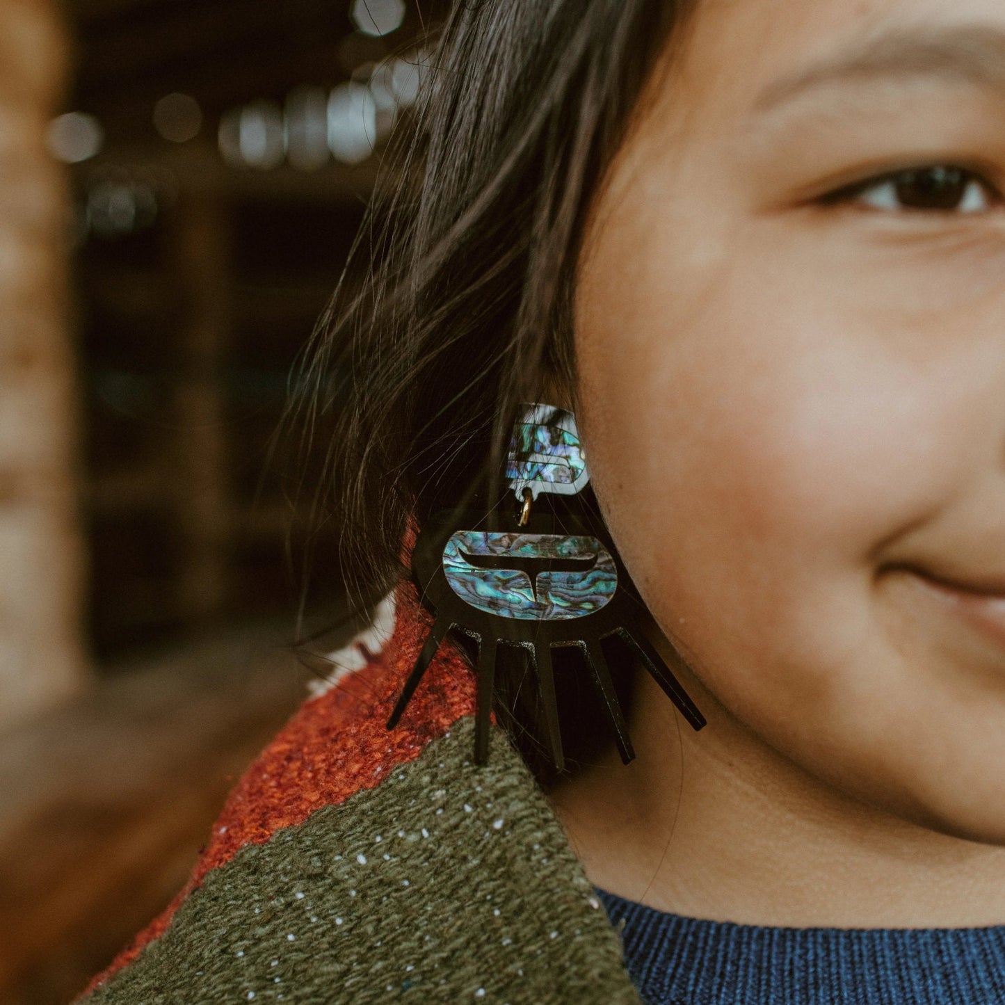 Closeup of a youth model wearing Urchin earrings in black acrylic from Copper Canoe Woman.