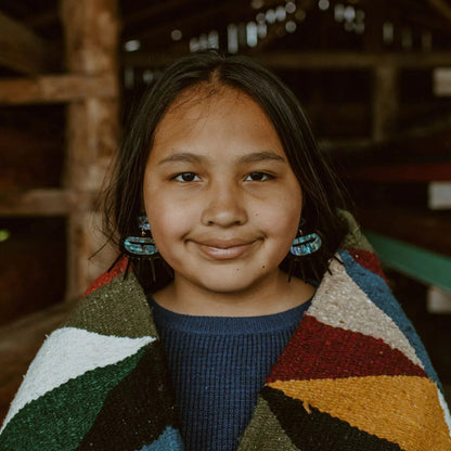 A youth model wearing black acrylic Urchin earrings from Copper Canoe Woman.