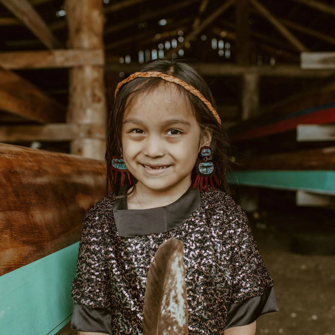 A youth wearing red translucent acrylic Urchin earrings from Copper Canoe Woman.