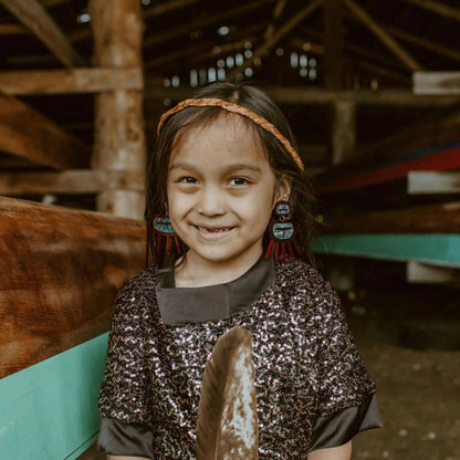 A youth wearing red translucent acrylic Urchin earrings from Copper Canoe Woman.