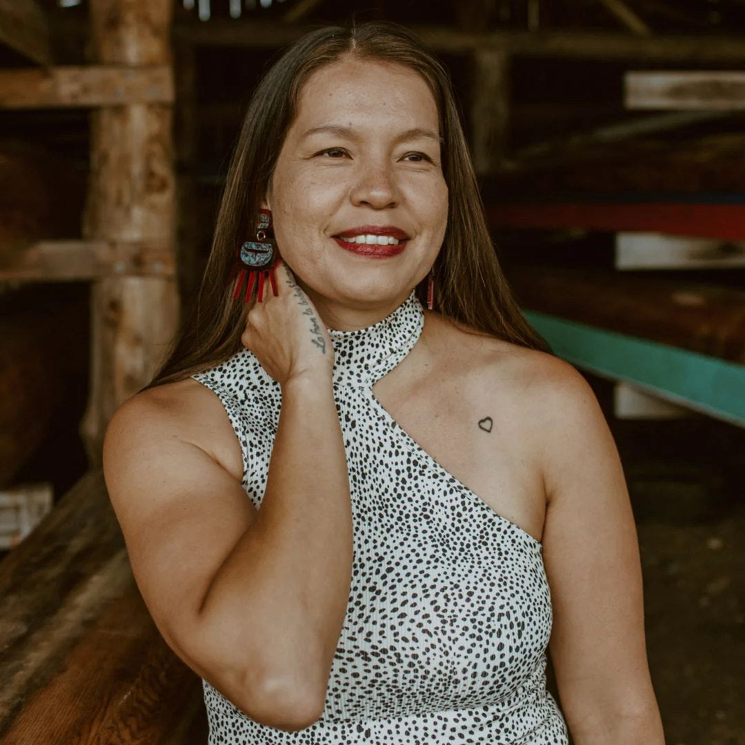 A woman wearing Urchin earrings from Copper Canoe Woman in red translucent acrylic.
